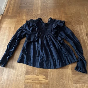 Svart blus med volanger och lång ärm - Supersnygg svart blus från Neo noir, knappast använd 