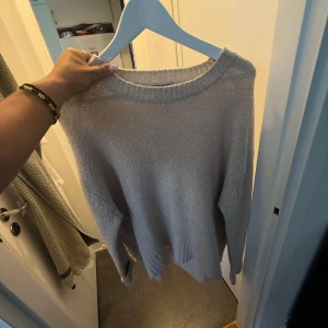 Beige stickad tröja med rund hals - Mysig beige stickad tröja med rund halsringning och långa ärmar. Tröjan har en avslappnad passform och ribbade muddar vid ärmslut och nederkant. Perfekt för lager-på-lager och chill höst- eller vinterstil.