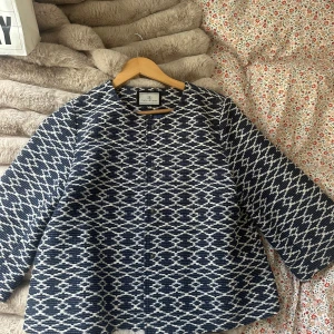 Mönstrad blåvit rock från Flash Woman - Säljer en snygg rock från Flash Woman i storlek M. Jackan är blå och vit med ett grafiskt mönster, har rund halsringning och knäppning framtill. Den är fodrad med blått tyg och har raka, lite vidare trelvartsärmar! Funkar att ha som jacka och en kofta inomhus💞💘