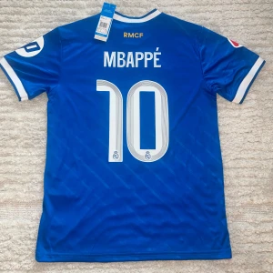 Mbappe real Madrid third 25/26 - Helt ny Mbappe tröja med prislapp, helt oanvänd. Med Laliga märke. Få tag på denna tröja innan Laliga starten!                    Anledningen till att dessa tröjor kostar lite mer än de andra är att jag betalade för FedEx expressfrakt och tull, och jag vill ge dig chansen att få tröjan innan ligan drar igång 🤝🏼  Mvh Zorro