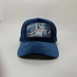 Real Madrid Ronaldo keps - Denna unika trucker keps är ett måste för fotbollsfans! Med glittrig finish och en framträdande bild av legendariska fotbollsspelare från Real Madrid (inkl. Cristiano Ronaldo) i en glädjescen.  Välj din stil: * Ikonisk Bild: Finns i fullfärg (blåtonad) eller klassisk . * Två Färger: Glittrande blåskimrande eller diskret blå  keps. * Komfort & Kvalitet: Klassisk trucker-design med nätpanel för ventilation och justerbar passform. Perfekt för att visa din passion för fotbol med still !!
