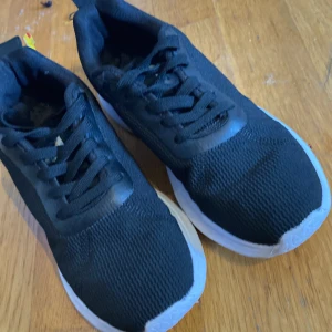 Svarta sneakers med vit sula - Svarta sneakers med vit, tjock sula och klassisk snörning. Ovandelen är i mesh-liknande syntetmaterial som andas och ger en sportig look. Perfekta för dig som gillar en clean och enkel stil.