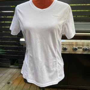 Vit tränings-tshirt från Swedemount - Vit sporttröja från Swedemount. Den har en V-ringning och korta ärmar. En liten logotyp finns på bröstet och en etikett med texten 'STX Quick Dry' finns på baksidan av nacken. Läng: 65 cm ﻿Bystvidd: 48 cm.  Inga bilder när den sitter på mig! Katter finns i hemmet!