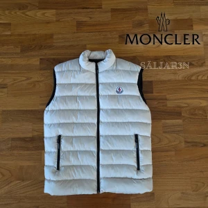 Moncler Väst - Letar du efter en stilren väst som kombinerar lyx och funktion? Denna Moncler-väst i vitt (storlek S) är i nyskick och perfekt för lager-på-lager eller som lätt ytterplagg. Tillverkad i slitstarkt nylon med dunfyllning. Broderad logga, innerfoder med serietryck och dragkedjefickor. Passar både till vardag och mer uppklätt.  📦 Snabb leverans – skickas samma dag vid köp! 📦 Hör av dig vid intresse eller om du har frågor!📌 #moncler #lyxmode #herrmode  