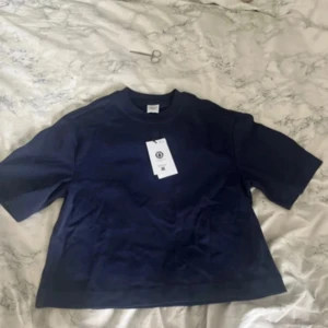 Marinblå t-shirt  - Säljer en marinblå t-shirt i storlek XXS. T-shirten har en loose passform, korta ärmar och rund halsringning. Helt oanvänd med prislappen kvar då jag har två likadana. Nypris 199kr, säljer för 99 men kan diskuteras vid snabb affär. Passar bra på mig som är 165cm