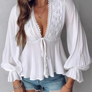 Vit blus - Råkade tyvärr beställa 2 styckna därav säljs denna. Helt oanvänd! Superfin vit blus med djup v-ringning, spetsdetaljer och knyt framtill. Vida, långa ärmar med resår vid ärmslut och flowig passform. 