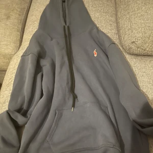 Blå hoodie från Polo Ralph Lauren - Mörkblå hoodie från Polo Ralph Lauren med klassisk röd broderad logga på bröstet. Tröjan har huva med svarta snören och en stor magficka. Perfekt för dig som gillar en chill och stilren look.