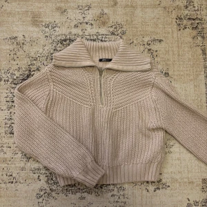Stickad tröja - Beige stickad tröja från Gina Tricot med dragkedja. Lite sliten i vänster ärm, och kan upplevas lite cropped. 