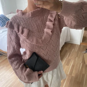 Rosa stickad tröja med volangdetalj🩷🥐 - Supersöt stickad tröja i ljusrosa med volangdetalj över bröstet och axeln. Tröjan har ett genombrutet mönster, rund halsringning och långa ärmar. Perfekt för dig som gillar romantisk och trendig stil💕💕