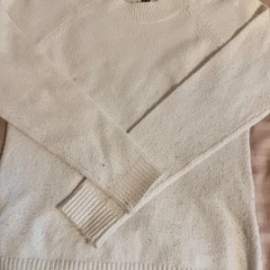 Vit stickad tröja från Vero Moda XS - Mysig vit stickad tröja från Vero Moda i storlek XS. Tröjan har rund halsringning, långa ärmar och breda ribbade muddar vid ärmslut och nederkant. Perfekt för lager-på-lager och passar till allt. Enkel och stilren design som funkar året runt.