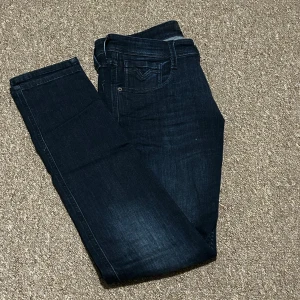 Mörkblå Replay Anbass jeans storlek 30/32 - Snygga mörkblå jeans från Replay, modell Anbass med slim fit. Utmärkt skick då de enbart har använts ett fåtal gånger, som ny!! De är super snygga till sommaren och passar till alla färger. Kom gärna med pris förslag!