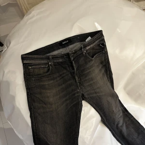 Replay svarta skinny jeans herr - Snygga svarta Replay jeans med tvättad look och klassiska fem fickor. Modellen är skinny fit med smal passform och normal midja. Jeansen har Replay-logga på bakfickan och patch i läder bak. Perfekta för en stilren och avslappnad outfit.