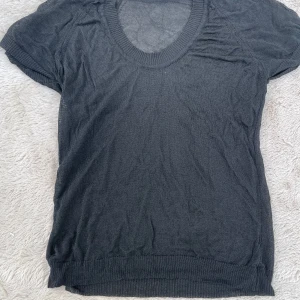 Svart tunn stickad kortärmad tröja - Mesh tröja. Svart tunn stickad tröja med korta ärmar och bred ribbad kant vid halsringning och nederkant. Tröjan är lätt transparent och har en avslappnad passform, perfekt för lager-på-lager. Enkel och stilren design som funkar till många looks.