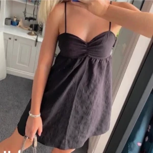 Svart kort klänning från H&M Divided - Svart klänning från H&M Divided med smala axelband och lätt rynkdetalj vid bysten.