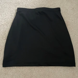 Svart enkel kortkjol från Shein - En stilren svart kortkjol med rak passform från Shein. Kjolen är basic och passar perfekt till många olika outfits. Tillverkad i ett mjukt och stretchigt material för en bekväm känsla hela dagen.