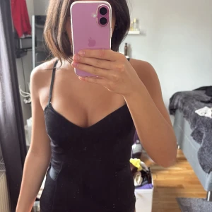 Svart tight kortklänning med smala axelband - Säljer en svart, tight korttopp med smala axelband och v-ringad urringning. Toppen har en figurnära passform och är perfekt .