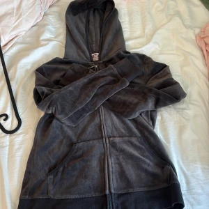Juicy Couture velour hoodie svart L - Storleken är L men har krympt i tvätten så är typ XS/S. Passar en 12-13 åring. Mysig svart velour hoodie från Juicy Couture med dragkedja och kängurufickor. Stor broderad Juicy Couture-logga i guld och rosa på ryggen med blingdetaljer och kronmotiv. Perfekt för en chill och trendig look. 