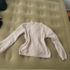 Ljusrosa stickad tröja från H&M - Mysig ljusrosa stickad tröja från H&M i storlek 164. Tröjan har rund halsringning, långa ärmar och ribbade muddar vid ärmslut och nederkant. Perfekt för dig som gillar en enkel och clean stil med en touch av pastell.