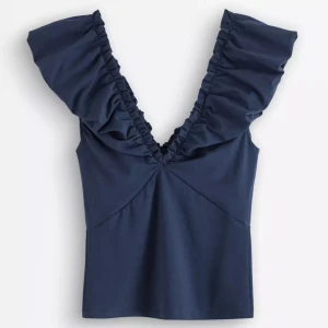 Volang-Topp - Supersnygg mörkblå topp med djup v-ringning och volanger längs axlarna. Helt ny, org pris; 299kr 💗