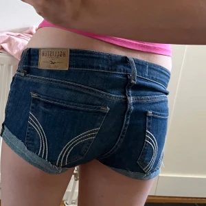 Mörkblå jeansshorts från Hollister - Snygga mörkblå jeansshorts från Hollister med låg midja och klassiska fem fickor. HAR SYTT DEM SJÄLV så dem är inte helt perfekta men är super fina på.💞Det står att det är W26 men sitter som W24!!