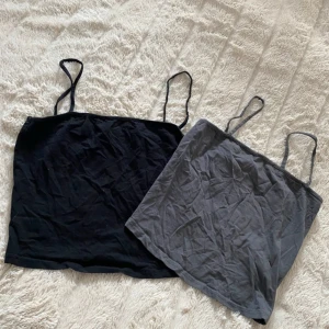 2-pack linne från H&M Divided S - Två enkla linnen från H&M Divided i storlek S. Ett är svart och det andra är mörkgrått, båda med tunna axelband och rak passform. Perfekta att styla lager på lager eller till jeansshorts. Gjorda i mjuk bomull för en skön känsla hela dagen.