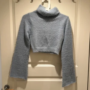 Ljusblå fluffig croppad polotröja - Supermjuk och fluffig ljusblå polotröja med croppad passform och långa ärmar. Perfekt för dig som vill ha en mysig men ändå trendig look. Hög polokrage och lätt oversized känsla i ärmarna.