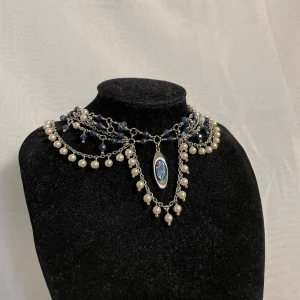 Handgjort halsband  - Ett silvrigt halsband med blåa och vita pärlor. Kedjorna och ståltråden är i rostfritt stål