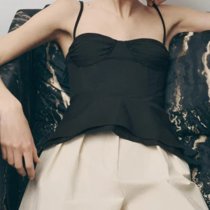 Svart topp med knytband - Supersnygg svart linnetopp med smala knytband över axlarna och söt sweetheart-urringning. Toppen har smockad rygg för extra komfort och sitter figurnära upptill. Perfekt att styla med jeans eller kjol för en trendig look. Strl men sitter som M