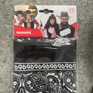 Svart och vit bandana med paisleymönster - Snygg svart bandana med klassiskt vitt paisleymönster från Milano Party Fashion. Perfekt accessoar för att ge din outfit en cool touch, särskilt till cowboy- eller temafester. Tunn och smidig att knyta runt halsen eller huvudet.