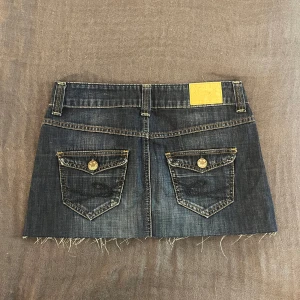 Mörkblå lågmidjad jeanskjol  - Skitsnygg mörkblå och lågmidjad jeanskjol från Esprit. Den har knappar på bakfickorna, sitter jätteskönt och är i storlek S. Perfekt för sommaren! 