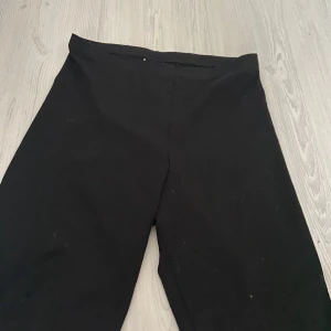 Svarta korta leggings från Gina Tricot - Svarta korta leggings från Gina Tricot i mjukt material med stretch. Byxorna har en enkel och clean look utan synliga detaljer, perfekta till både oversized hoodies och crop tops. Perfekta nu till sommaren. 
