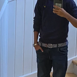 Lyle and scott tröja - Snyggt bälte med blåvitt randigt mönster och bruna läderdetaljer vid spännet. Bältet har en klassisk form och passar perfekt till jeans. Den stickade looken ger en cool och avslappnad vibe.