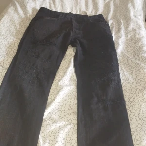 Svarta jeans från Dsquared2, stl 44 - Säljer ett par svarta jeans från Dsquared2 i storlek 44. Jeansen har slitna detaljer framtill för en edgy look och klassisk femficksdesign, pris kan diskuteras vid snabb affär