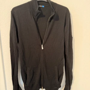 J.Lindeberg kofta - Svart stickad kofta från J.Lindeberg med hel dragkedja framtill och två fickor. 