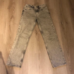 Grå straight jeans från Gant - Snygga grå jeans från Gant med stentvättad look och klassisk femficksdesign. Modellen är straight med normal passform och har en ljusgrå ton. Jeansen har bälteshällor och Gant-logga på bakfickan. Perfekt för dig som gillar stilrena och tidlösa jeans.