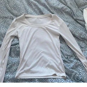 Vit långärmad topp i bomull - Enkel och stilren vit långärmad topp med rund halsringning. Tillverkad i mjuk bomull, perfekt att matcha med jeans eller kjol för en clean look. Snygg bas som funkar året runt.