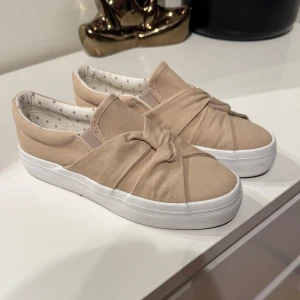 Beige skor från Anna Field - Snygga slip-on sneakers i beige från Anna Field. Använd bara nån gång, så finns små tecken på att dom varit ute men ser i princip nya ut