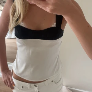 Svartvit linnetopp med breda axelband - Säljer en snygg svartvit linnetopp med breda axelband och fyrkantig urringning. Toppen har svart parti upptill och resten är vit, vilket ger en stilren kontrast. Perfekt att matcha med jeans eller kjol för en trendig look.