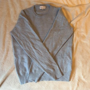 Ljusblå kashmirtröja från Davida - Supermjuk ljusblå kashmirtröja från Davida med rund halsringning och långa ärmar. Klassisk och stilren modell med ribbade muddar vid ärmslut och nederkant. Perfekt för lager-på-lager. Liten defekt vi axeln inget som stör alls. 2600 ny pris