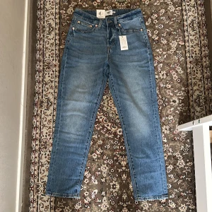 Blå high waist jeans från 157 Cone - Snygga blå jeans från 157 Cone i modellen high waist mom fit. Klassisk femficksdesign med raka ben och ljus tvätt. Jeansen har en brun läderpatch bak i midjan och är gjorda i slitstarkt bomullsjeansmaterial. Perfekt för dig som gillar en chill och tidlös look. W27-28, storlek S.