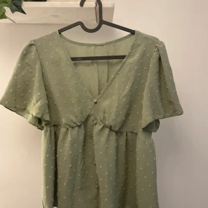 Grön blus  - Säljer en söt ljusgrön blus med v-ringad front och små knappar. Perfekt för vår och sommar!