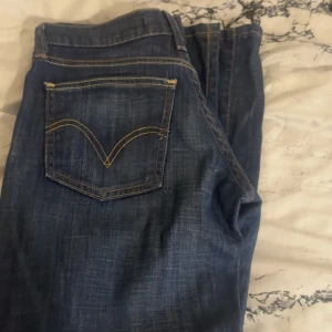 Levis blå jeans bootcut - Säljer ett par klassiska Levis  jeans i mörkblå tvätt med snygga kontrastsömmar och fem fickor. Modellen har rak passform med lätt bootcut och normal midja. Perfekta för dig som gillar tidlös denimstil och vill ha ett par jeans som funkar till allt.   Står ej storlek men skulle säga XS