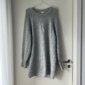 Grå stickad klänning från Topshop - Mysig grå stickad klänning från Topshop i storlek M. Klänningen har en rund halsringning, långa ärmar med ribbade muddar och en loose fit. 