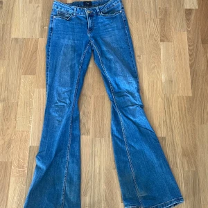 Blå bootcut jeans från Vero Moda - Snygga blå jeans från Vero Moda med klassisk femficksdesign och bootcut-ben. Jeansen har normal midja och är tillverkade i mjukt denimtyg som sitter skönt. Perfekta för dig som gillar en retroinspirerad look med utsvängda ben.