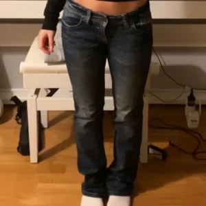 Lågmidjade raka jeans - Snygga blå jeans, köpte second hand. Lådmidjade och raka i modellen. Det står storlek W 34 och L 30 men de passar mig som ofta har storlek 36. Jeansen har slitningar och ljusare partier framtill och bak, samt detaljerade sömmar och QS-brodyr på fickan. 