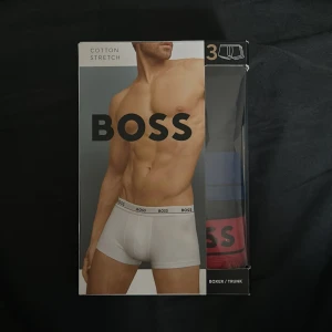3-pack BOSS boxerkalsonger i bomull - Helt nya! 3-pack boxerkalsonger från BOSS i stretchig bomull. Färgerna är svart, blå och röd med klassisk BOSS-logga på midjeresåren. Modellen är tight och kortare i benen, perfekt för dig som gillar en sportig och stilren look.