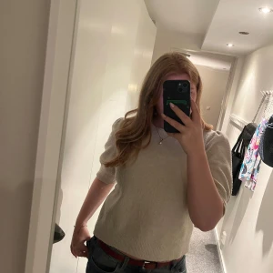 Beige stickad tröja med puffärm - Säljer en beige stickad tröja med puffade korta ärmar och rund hals. Perfekt för dig som gillar enkel och stilren look med en twist på ärmarna.