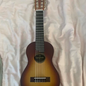 Guitalele från Yamaha - Säljer en guitalele, den har storleken som en ukelele men den har 6 strängar. Den har lite skador på sista bilden, men det inget man märker och den är i jätte fint skick💕