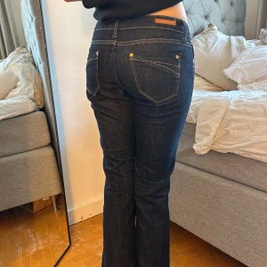 Mörkblå jeans från Cross Jeans - Snygga mörkblå jeans från Cross Jeans.  Jeansen har kontrastsömmar, klassiska fem fickor och låg midja. Perfekta för dig som gillar en tidlös look. Straight jeans. Bootcut jeans. Raka jeans.