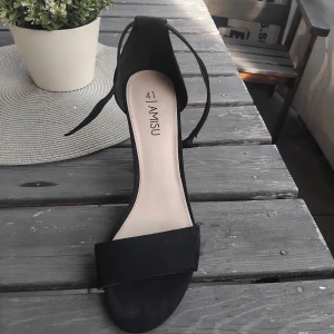 Svarta klackade sandaler från Amisu - Stilrena svarta sandaler från Amisu med bred rem över tårna och öppen tå. Skon har en chunky hög klack och smal rem runt vristen som knyts. Ytan är i mockaliknande material och sulan är svart. Perfekt för dig som gillar minimalistisk och trendig look. Kom gärna med prisförslage😇😊
